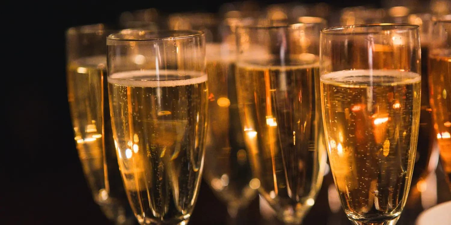 Rows of filled champagne flutes catching the light at an evening event.